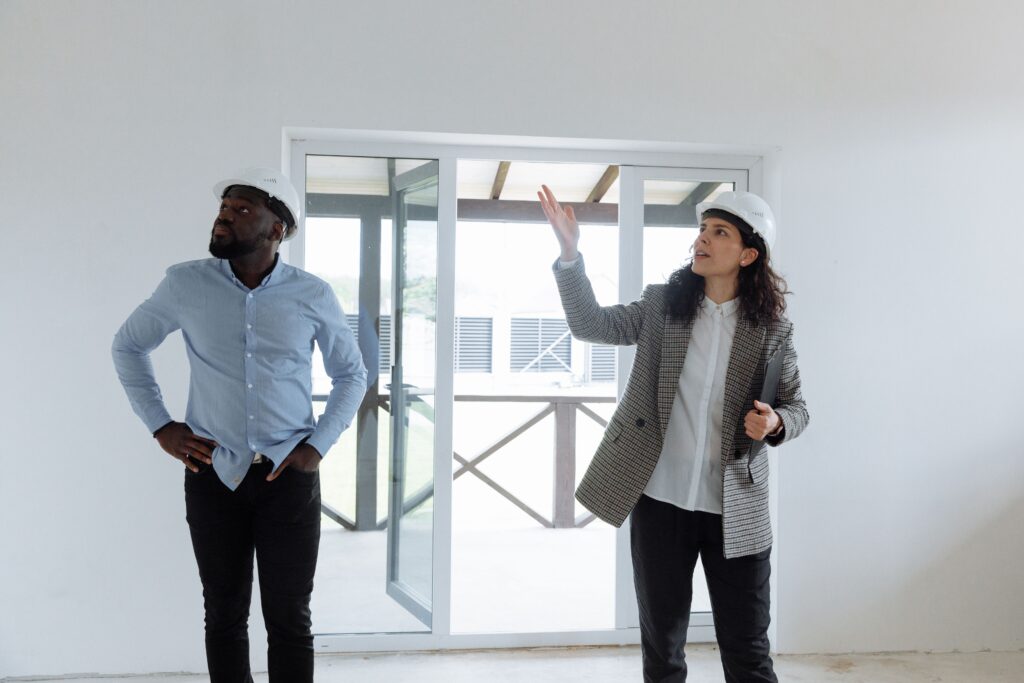 Two contractors reviewing a home interior while wearing hard hats